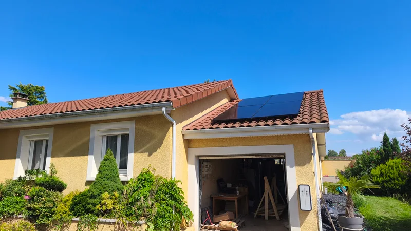 Maison jaune avec garage, panneaux sur le pan du toit